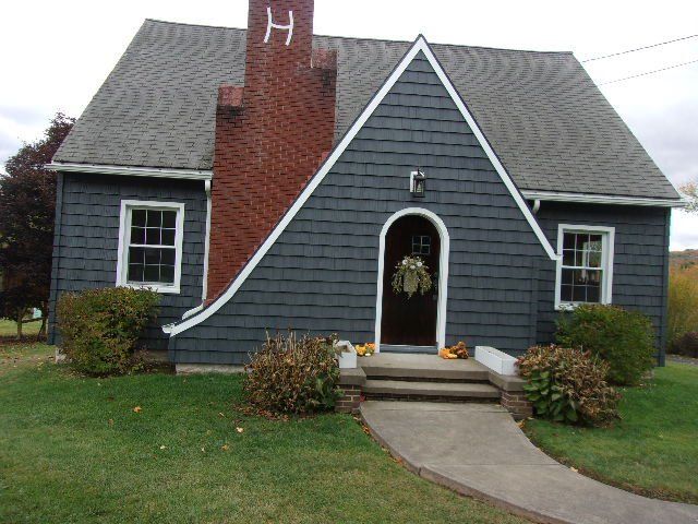 Cottage with Deep Granite shake siding, arched front door and brick chimney
