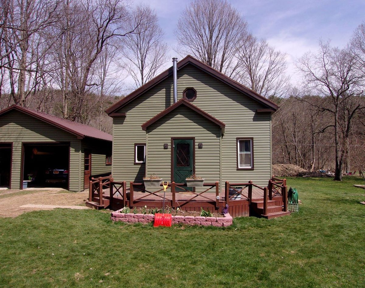 Green vinyl-sided cottage with a new front deck and matching detached garage