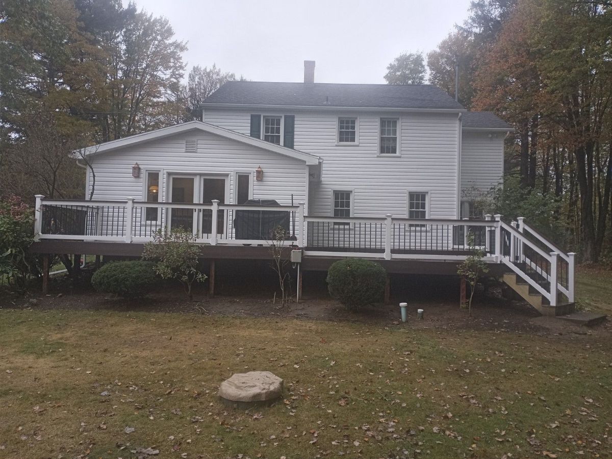 Rear deck with white railing and stairs on a two-story home