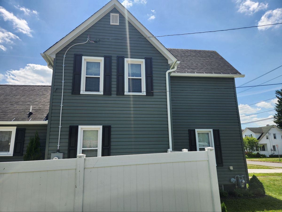 Slate-gray siding with black shutters behind a white vinyl privacy fence